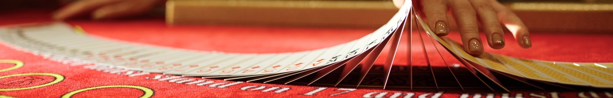 Croupier shuffling cards on a red felt table