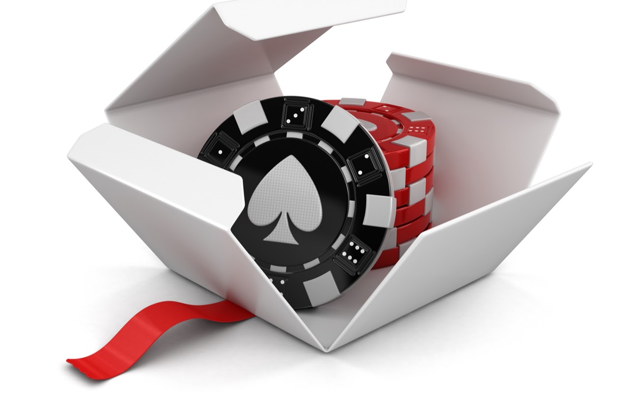 Red and black casino chips in an open white gift box with red ribbon.