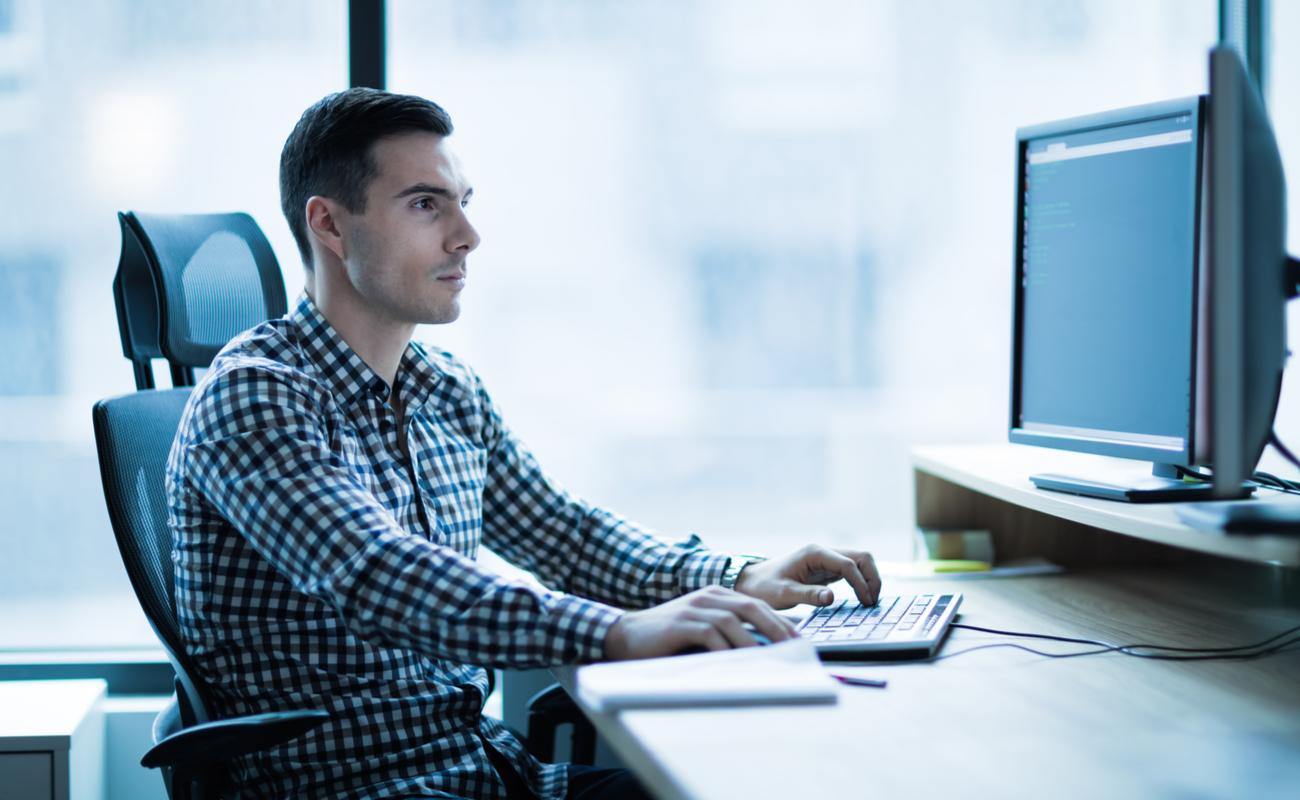 A man works on his dual-screen desktop PC.