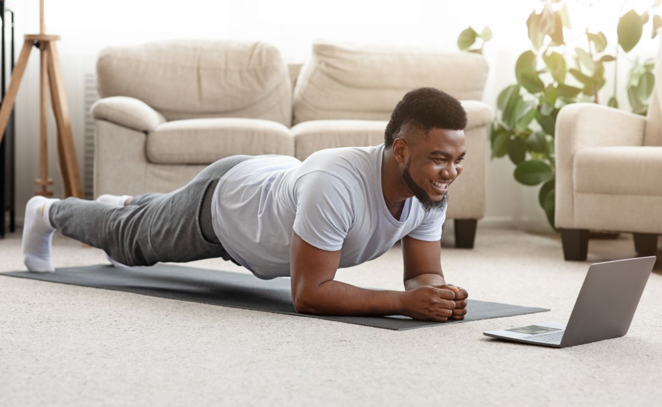 A man doing a plank exercise in front of his laptop.