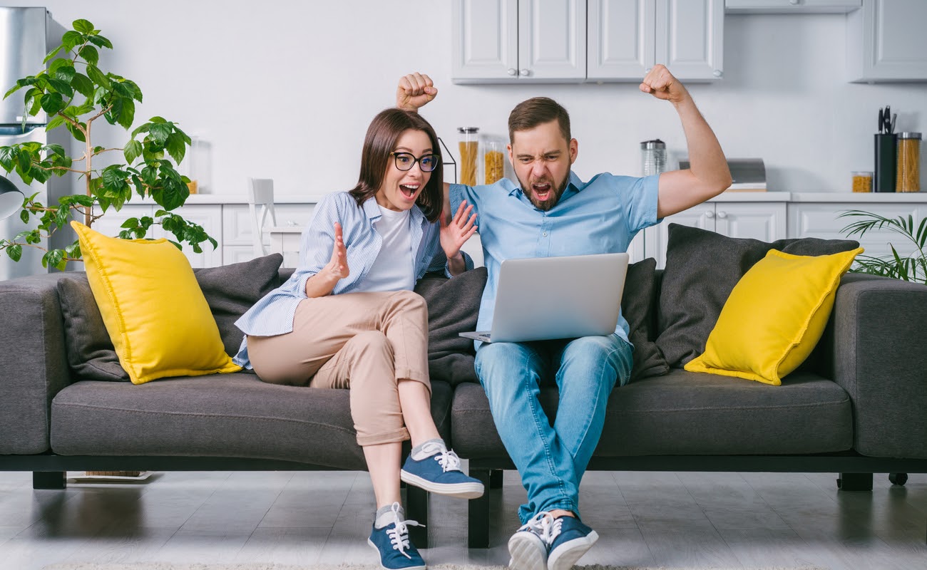 Excited couple playing online casino games on a laptop computer.