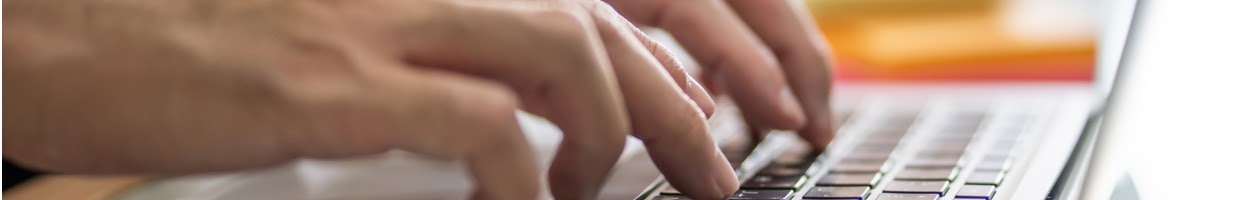 Close-up of a man’s hands typing on a laptop.