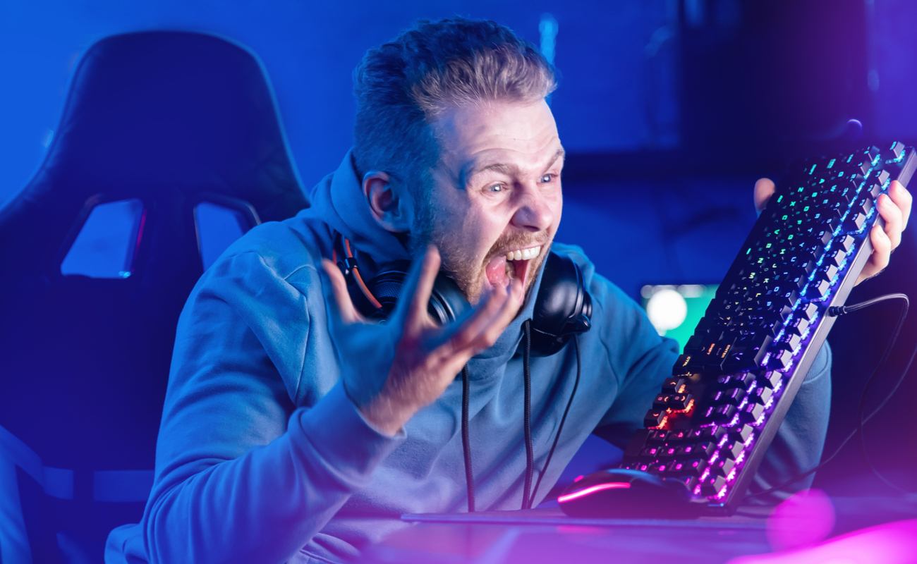 An angry gamer raises his keyboard in frustration.