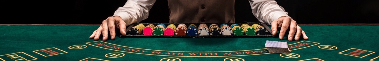 A croupier with playing cards and gambling chips at a casino table.