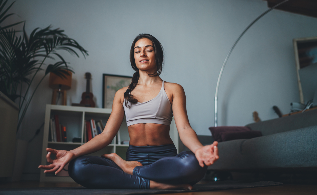 A woman meditating in her living room.