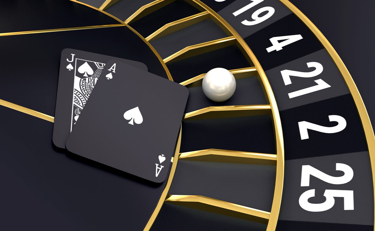 3D concept of a black roulette wheel with a ball, an Ace and a Jack playing card on it.