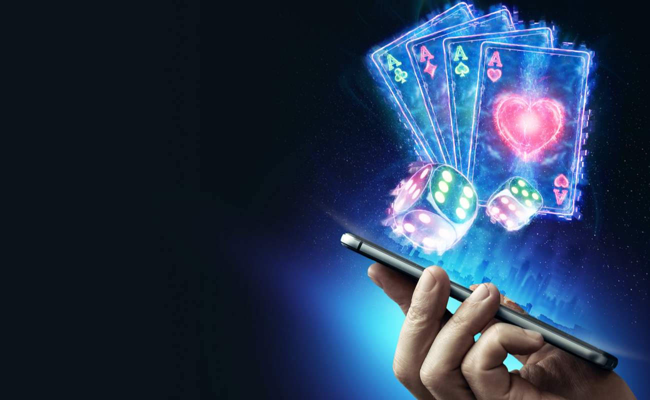 Online casino concept with a hand holding a smartphone with dice and playing card symbols above the screen.