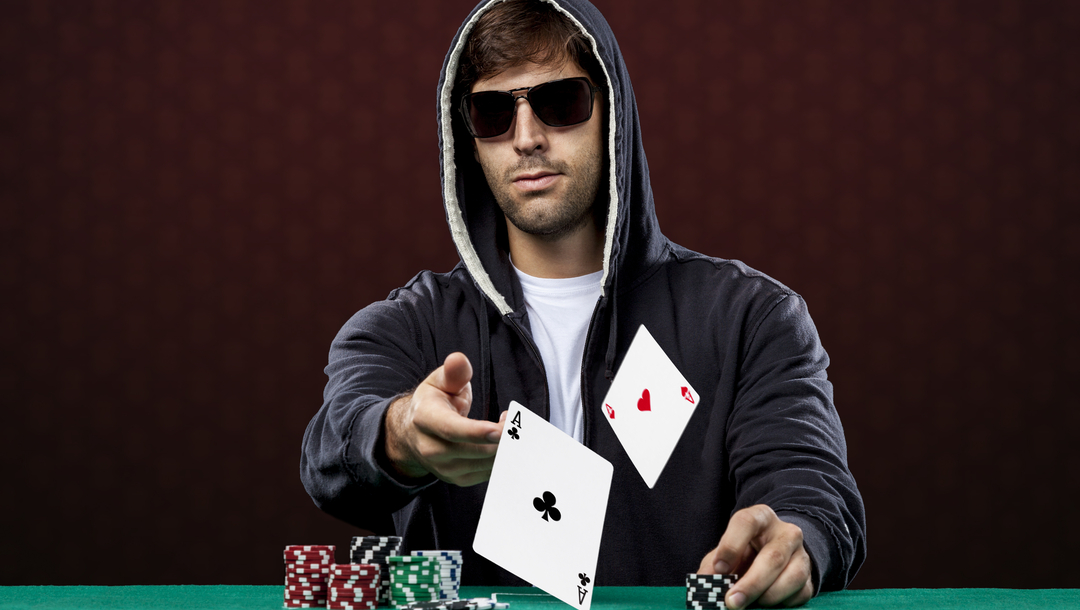 Poker player, against a black background, throwing two ace cards.