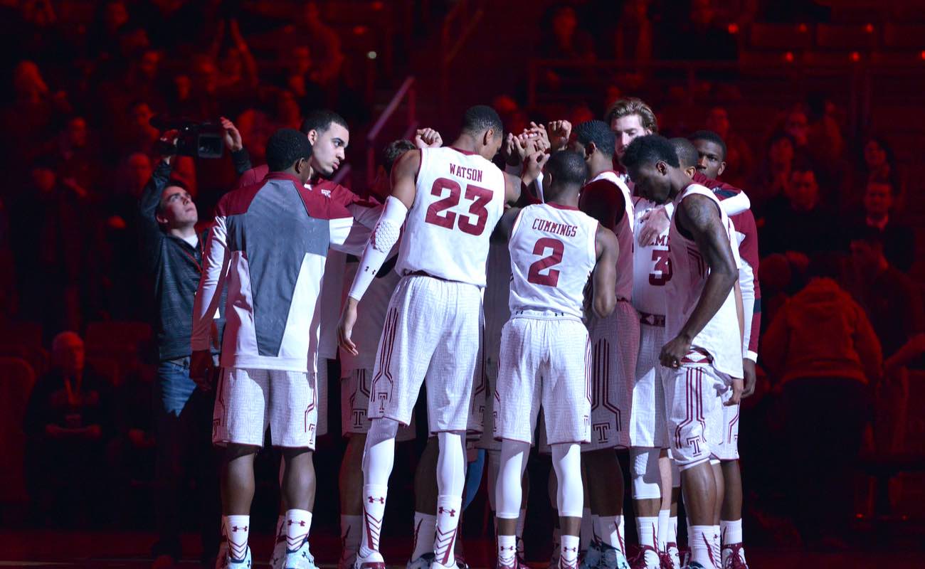 The Temple University basketball team huddle as the arena is still lit in red