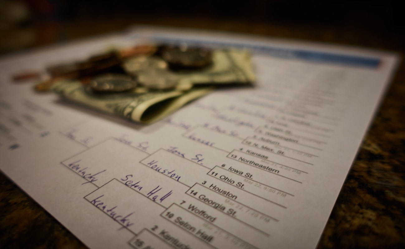 Money on top of a printed 2019 March College Basketball Tournament bracket