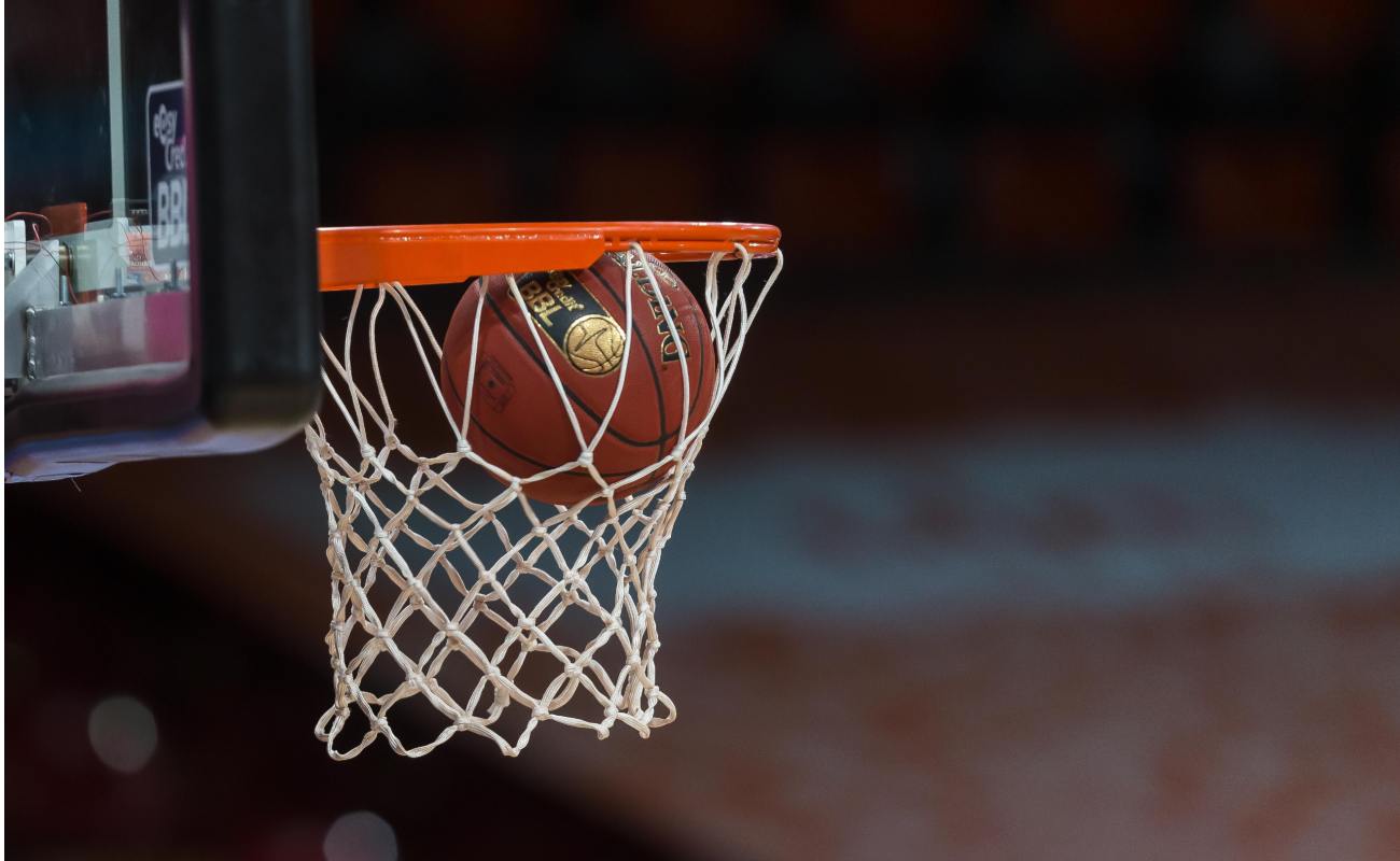 A basketball going through the hoop into the side netting