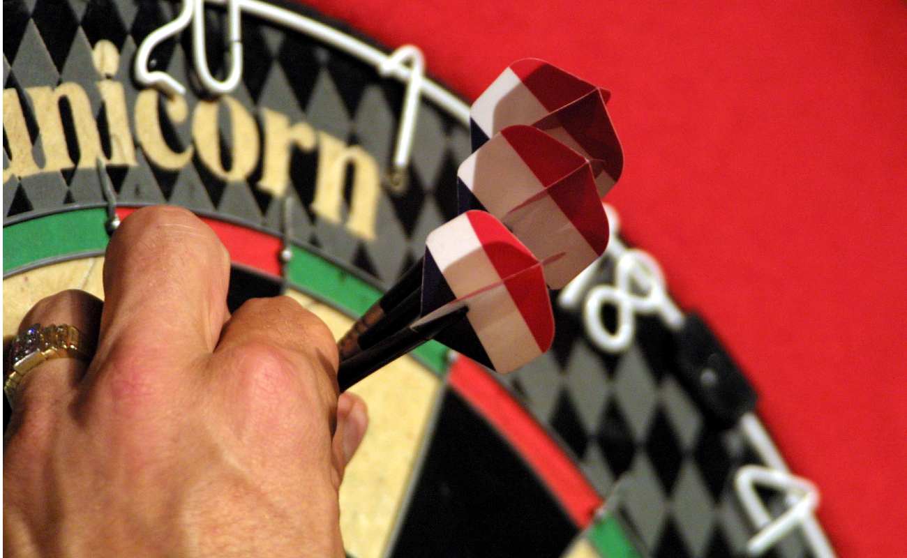 A hand taking darts out of a dart board