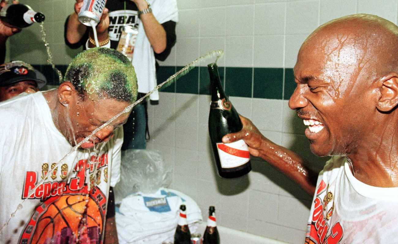Dennis Rodman of Chicago Bulls gets beer and champagne poured on head by teammate Michael Jordan after winning NBA Finals