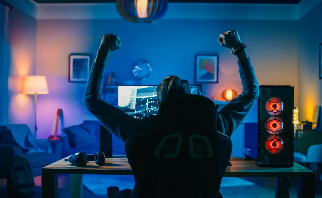 Gamer with arms in the air sitting in front of a desktop