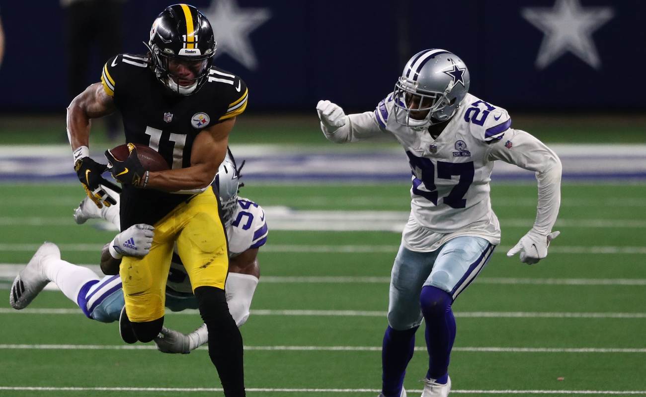 Chase Claypool runs the ball past two members of the Dallas Cowboys.