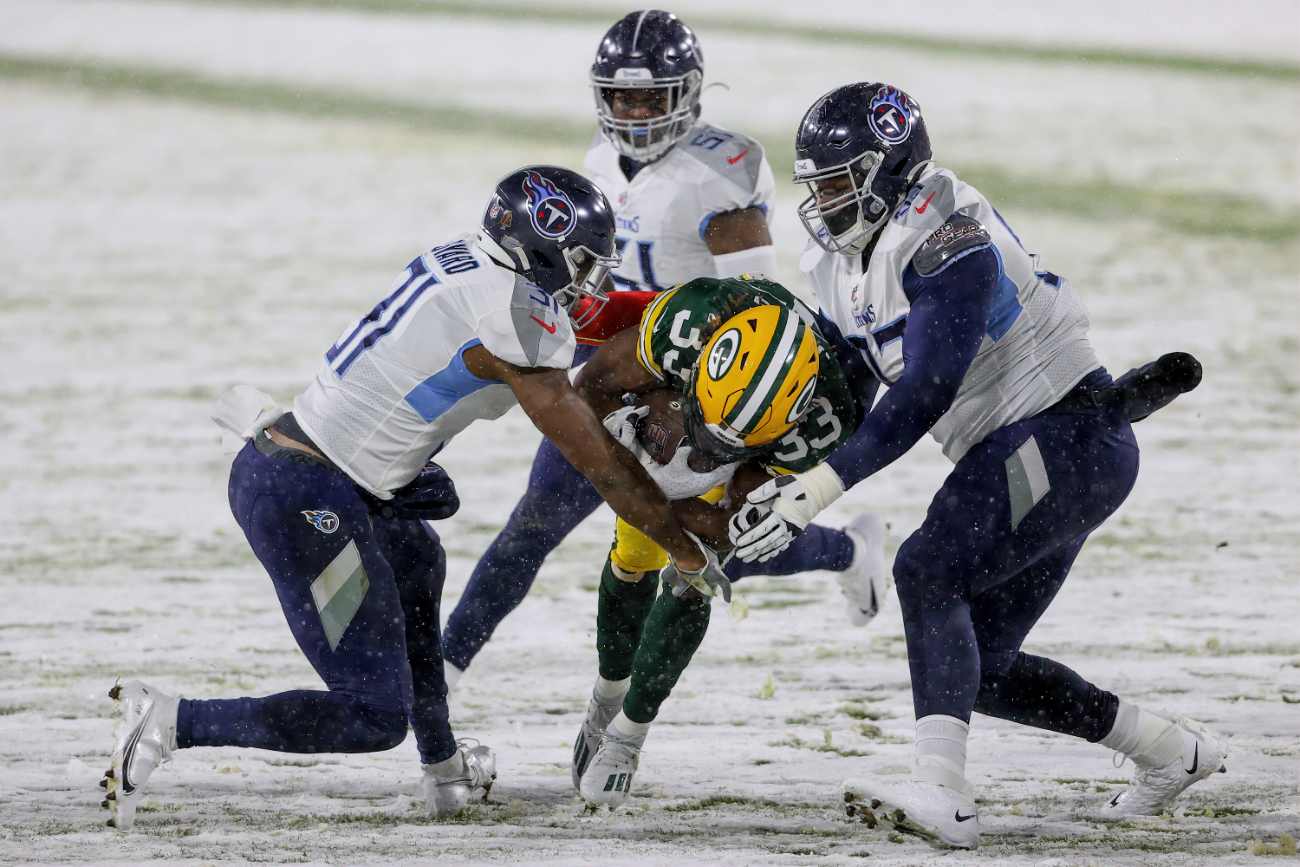 Aaron Jones #33 of the Green Bay Packers runs with the ball while being tackled by Kevin Byard #31 and Teair Tart #93 of the Tennessee Titans in the first quarter at Lambeau Field on December 27, 2020 in Green Bay, Wisconsin. (Photo by Dylan Buell/Getty Images)