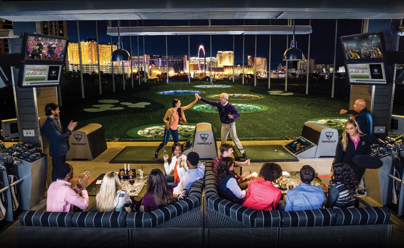 MGM Grand & Topgolf Las Vegas with people playing during the evening and the night view showing from the windows.