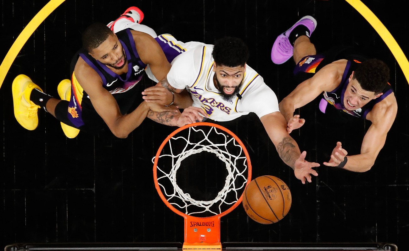 Anthony Davis #3 of the Los Angeles Lakers reaches for a rebound over Mikal Bridges #25 and Devin Booker #1 of the Phoenix Suns during the second half of Game One of the Western Conference first-round playoff series at Phoenix Suns Arena on May 23, 2021 in Phoenix, Arizona. The Suns defeated the Lakers 99-90. (Photo by Christian Petersen/Getty Images)